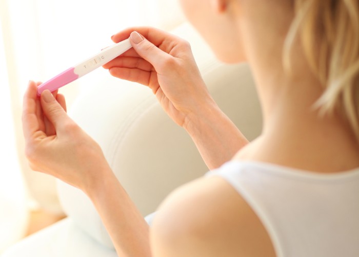 Frau hält negativen Schwangerschaftstest bei unerfülltem Kinderwunsch