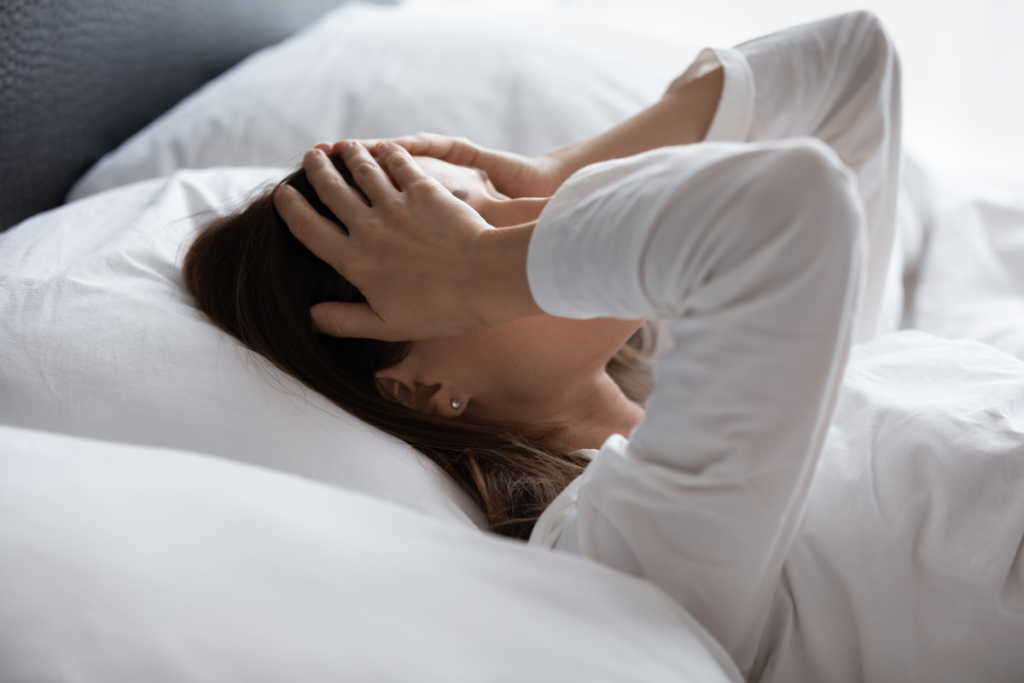 Stress und Schlafmangel - gestresste Frau liegt im Bett. Dieser Schlafmangel kann sich auf Stimmung, Immunsystem und den Darm auswirken.