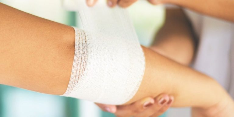 Frau verbindet Wunde einer anderen Person