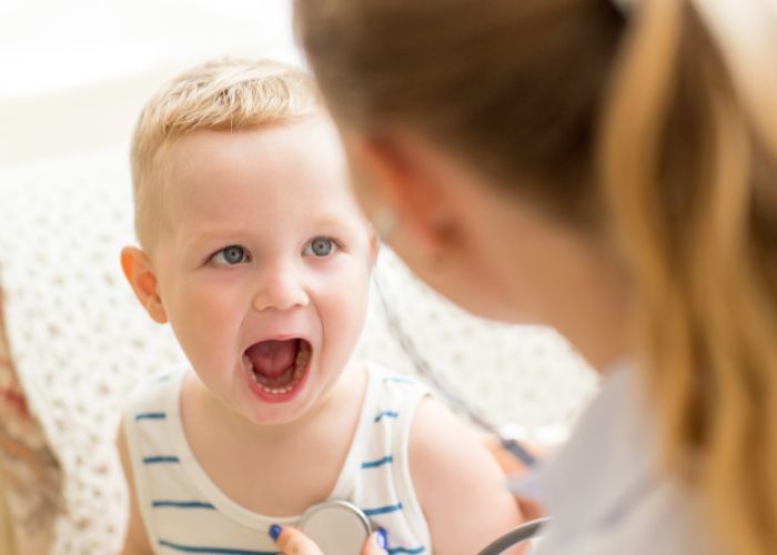 Mund-Mikrobiom: Kind zeigt seine Mundhöhle einer Ärztin