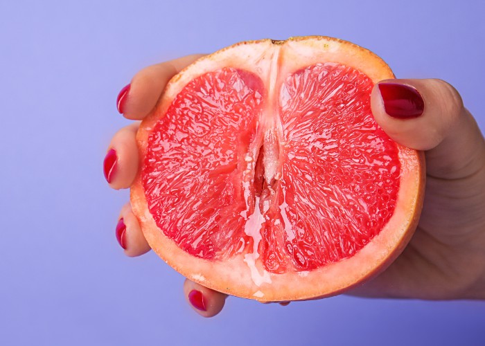 Frau hält eine Grapefruit als Symbol für gesunde Scheidenflora