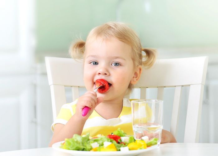 Immunstarke Ernährung für Kinder: kleines Mädchen isst Gemüse