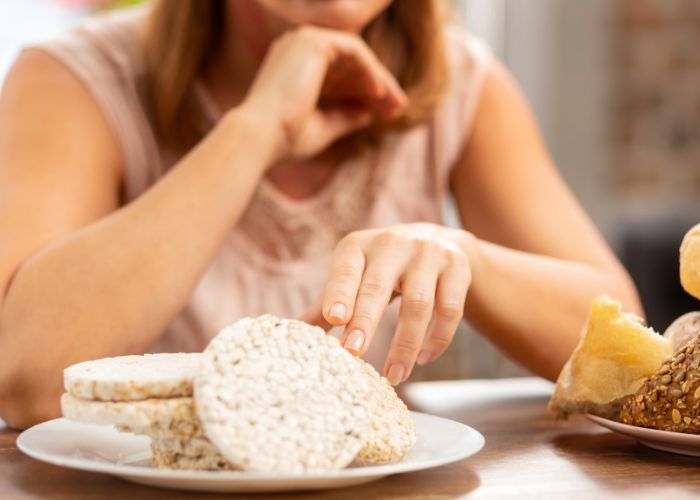 Frau sitzt vor glutenhaltigen Lebensmitteln