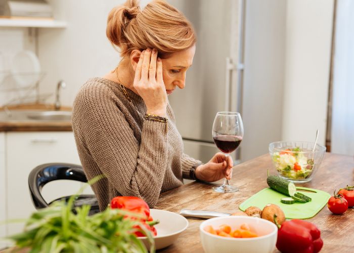 Histaminintoleranz: Frau trinkt Glas Rotwein und hat Kopfschmerzen